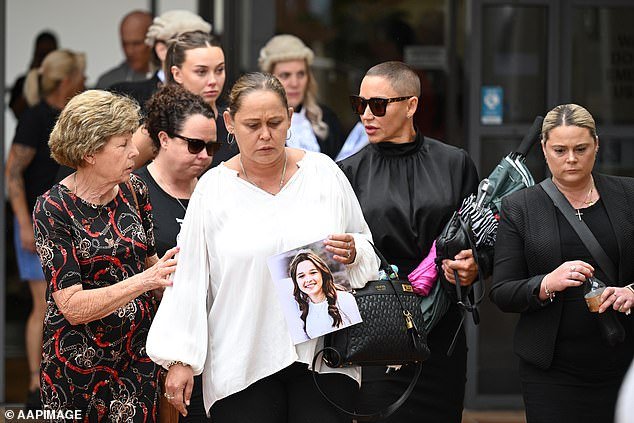 Samantha Trimarchi (dressed in white top) carries a photo of her daughter Gabby McLennan, who was one of the victims of the Buxton car crash that killed five teenage friends