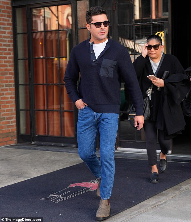 Muscular shape: Zac Efron showed off his muscular shape in a navy blue V-neck sweater and a white crew-neck T-shirt underneath.  The Gold star wore jeans with brown ankle boots as he left the Bowery Hotel in New York on Monday