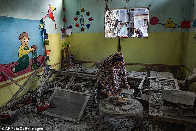 A woman tries to save some books in a daycare center that was hit by an Israeli bomb attack in Rafah on Saturday