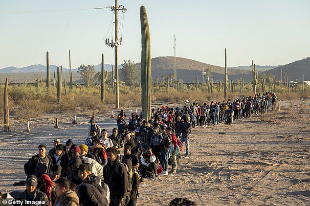 Immigrants line up at a remote U.S. Border Patrol processing center after crossing the U.S.-Mexico border in Lukeville, Arizona, on Thursday.  A wave of immigrants illegally passing through openings cut into the border wall by smugglers has overwhelmed U.S. immigration authorities, causing them to close several international ports of entry so agents can help process the new arrivals.  (Photo by John Moore/Getty Images)