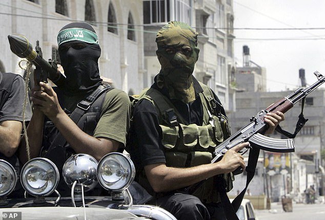 FILE – Palestinian militants from Hamas ride on a truck with their weapons