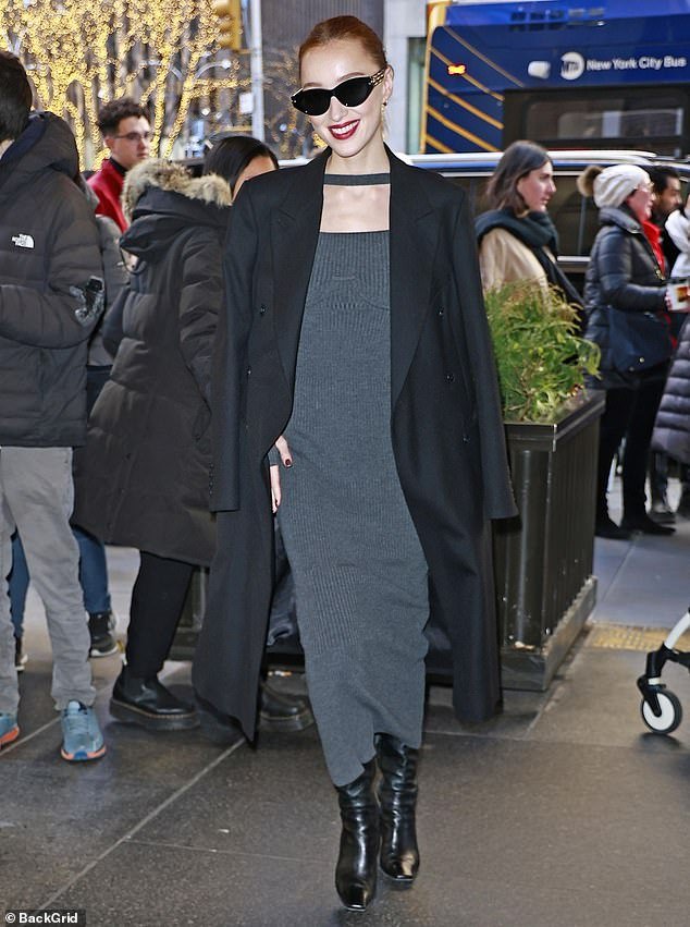 She wore a black coat, but over her shoulders, and completed her look with a pair of black heeled boots
