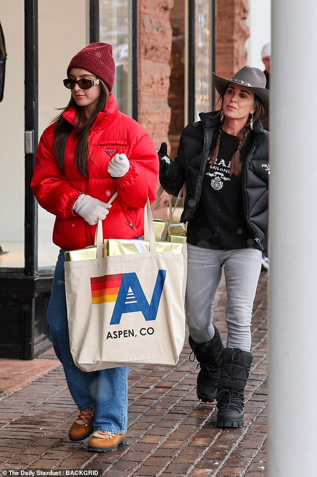 A cowboy hat covered her long brown hair and she carried a bag from the trendy store Aviator Nation