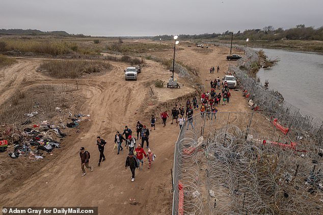 Migrants walk along the banks of the Rio Grande after crossing the border into Eagle Pass, Texas, one of a number of border towns hampered by this year's massive influx of migrants