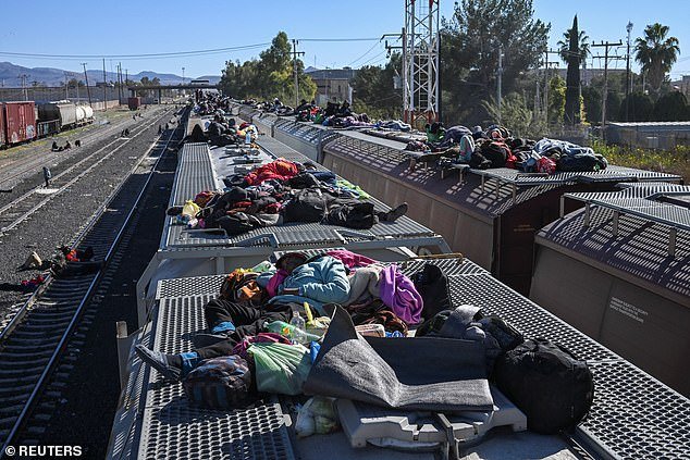 Migrants rest on train cars as they wait for a freight train to travel to the US border, at a rail yard in Chihuahua, Mexico
