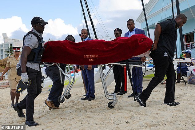Mortuary services staff transport the body of a female tourist after what police described as a fatal shark attack in the waters near the Sandals Royal resort in Bahamas