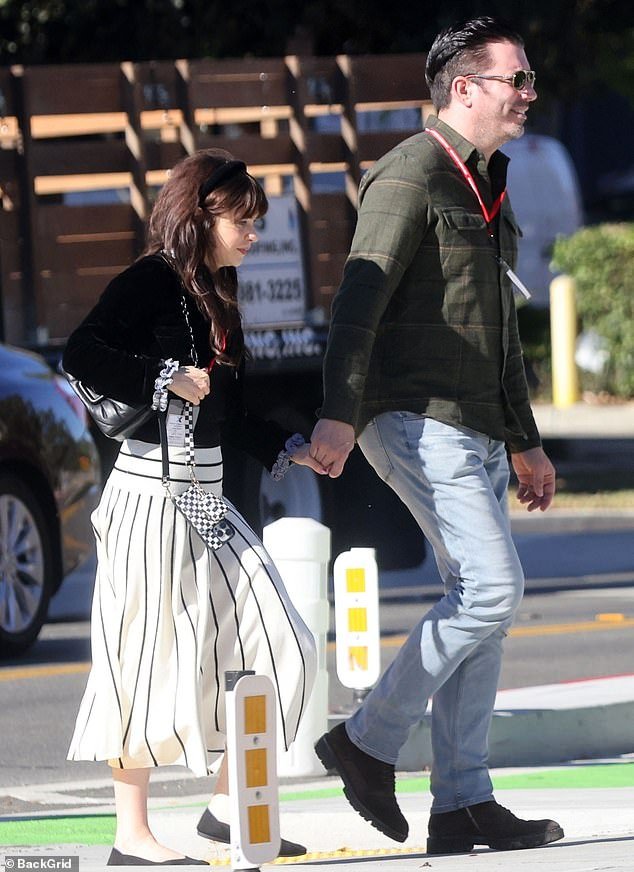 Deschanel wore a black button-up top tucked into a striped maxi skirt as she spent time with Scott
