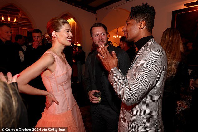 The actress added a pop of color to the peach dress and wore a pop of bright pink lipstick (pictured chatting with Matthew Heineman and Jon Batiste)