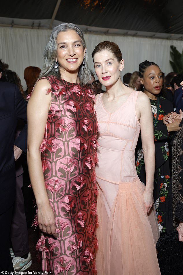 The actress added a pop of color to the peach dress and wore a pop of bright pink lipstick (pictured with Vanity Fair editor-in-chief Radhika Jones)