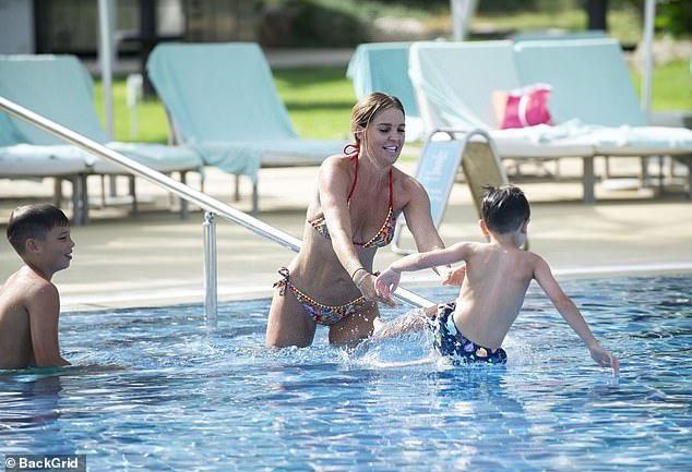 The 40-year-old model turned heads in the multicolored paisley print two-piece as she showed off her washboard abs while playing in the pool with her sons