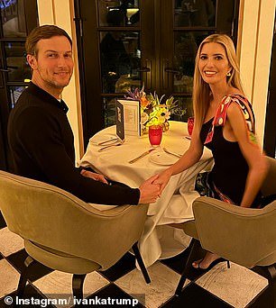 The couple hold hands as they sit at a table for two