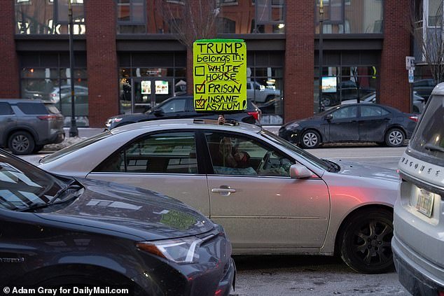 A New Hampshire resident driving outside a canceled DeSantis event on Sunday holds up a sign saying Trump belongs in 'jail' or an 'insane asylum'