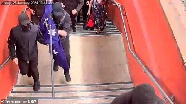 The men (pictured) dressed in all black were seen holding an Australian flag while another man who was part of the group held a shield