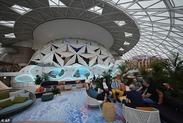 Passengers lounge in the Aquadome area of ​​Icon of the Seas, a diving and performance venue under a glass dome on the top of the ship