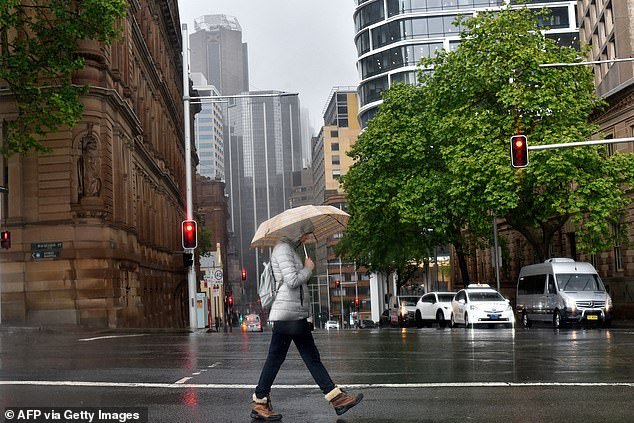 A woman sheltered from the rain under an umbrella as she crossed a street in Sydney last year