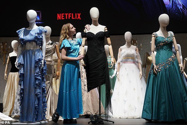 Pictured: A gallery assistant adjusts a reproduction of Princess Diana's revenge dress, part of the collection of more than 450 costumes, sets and props from the Netflix series