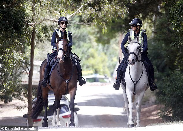 Police on horseback walk past the Murphy compound on Wednesday as the search enters its fourth day