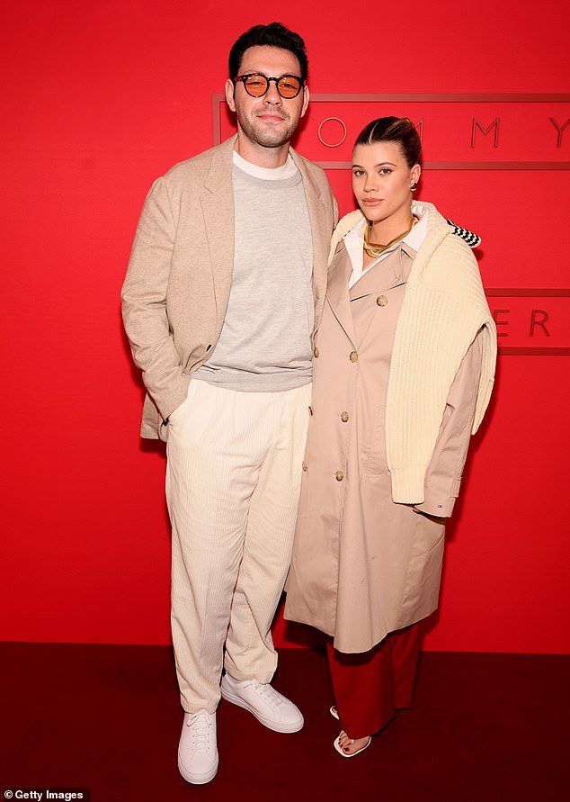 The label's new brand ambassador wore a chic tan trench coat as she arrived at the party with her handsome husband Elliot Grainge