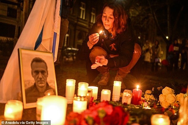 Supporters of the late Russian opposition leader hold banners and place candles around a makeshift monument in Krakow, Poland