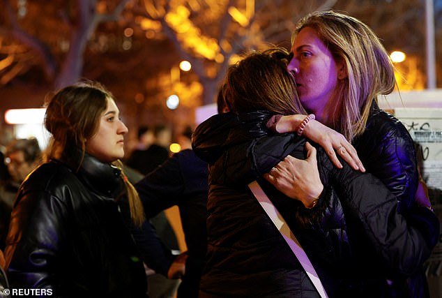 Devastated residents comfort each other at the scene of the massive fire in the Campanar area