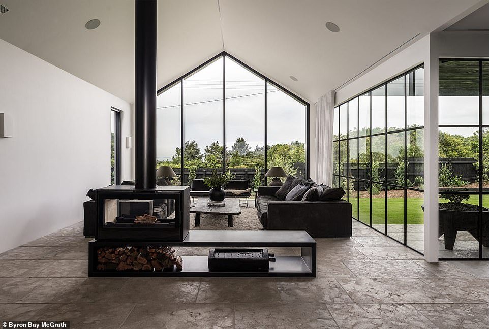 The open-plan living room, kitchen and dining room are the epicenter and brightest room of the house with white walls and ceiling-high windows with limestone floors letting in natural light