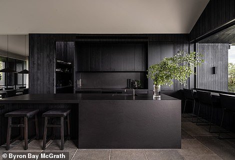 Unlike the rest of the family room, the kitchen is all black, from the island bench to the backsplash, cabinets, hidden bar and even the sink