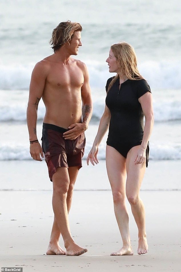 The pop star and the handsome surf instructor enjoy each other's company on the sand