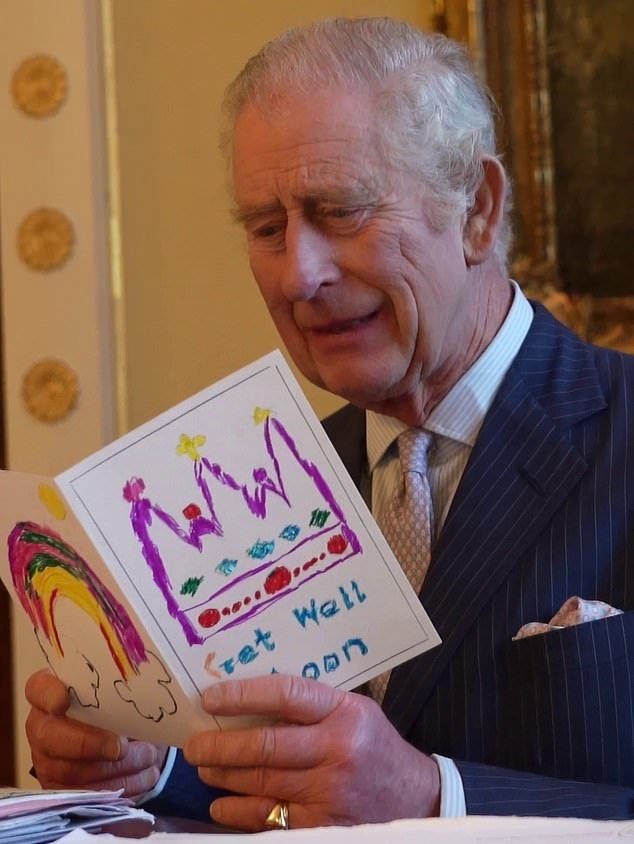 The King opens a card with hand-drawn images of a rainbow and a multi-colored crown sent to Buckingham Palace by a child