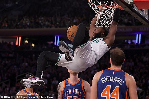 Jaylen Brown hangs from the rim after a dunk against Knicks guard Josh Hart on Saturday