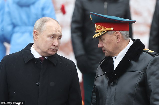 Russian President Vladimir Putin listens to Defense Minister Sergei Shoigu taking part in the wreath-laying ceremony at the Tomb of the Unknown Soldier on the occasion of Defender of the Fatherland Day on Friday