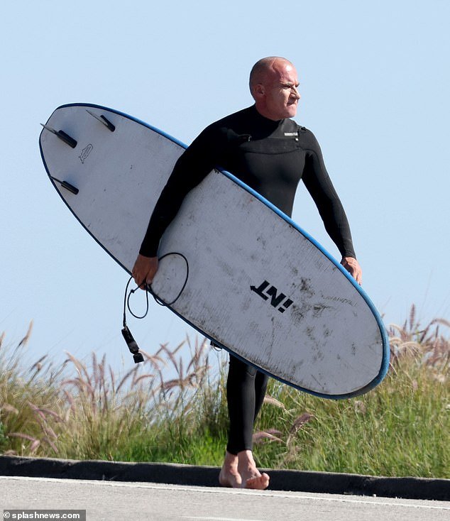 He was seen carrying his board and walking barefoot to the shore