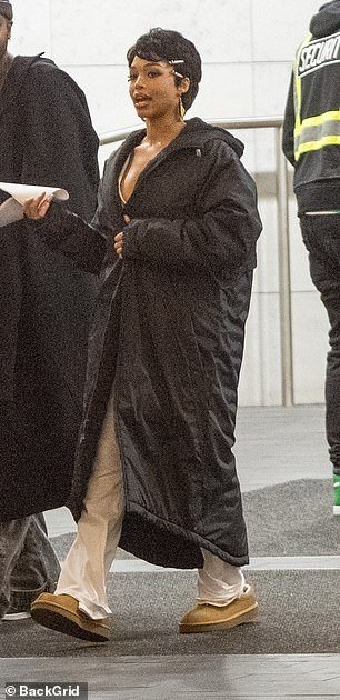 The influencer donned an oversized black padded coat and a pair of comfy slippers as she walked around the set with a crew member.