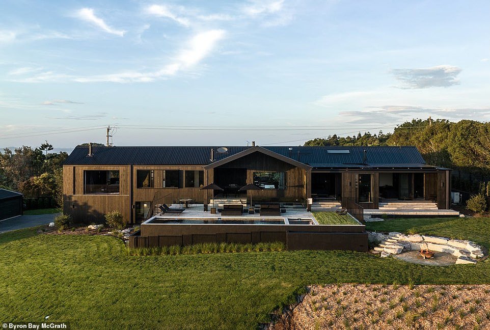 Perched atop a hill in a picturesque rural setting lies an atmospheric lodge estate with an all-black facade and interior that will wow home enthusiasts for its elegant, minimalist style.