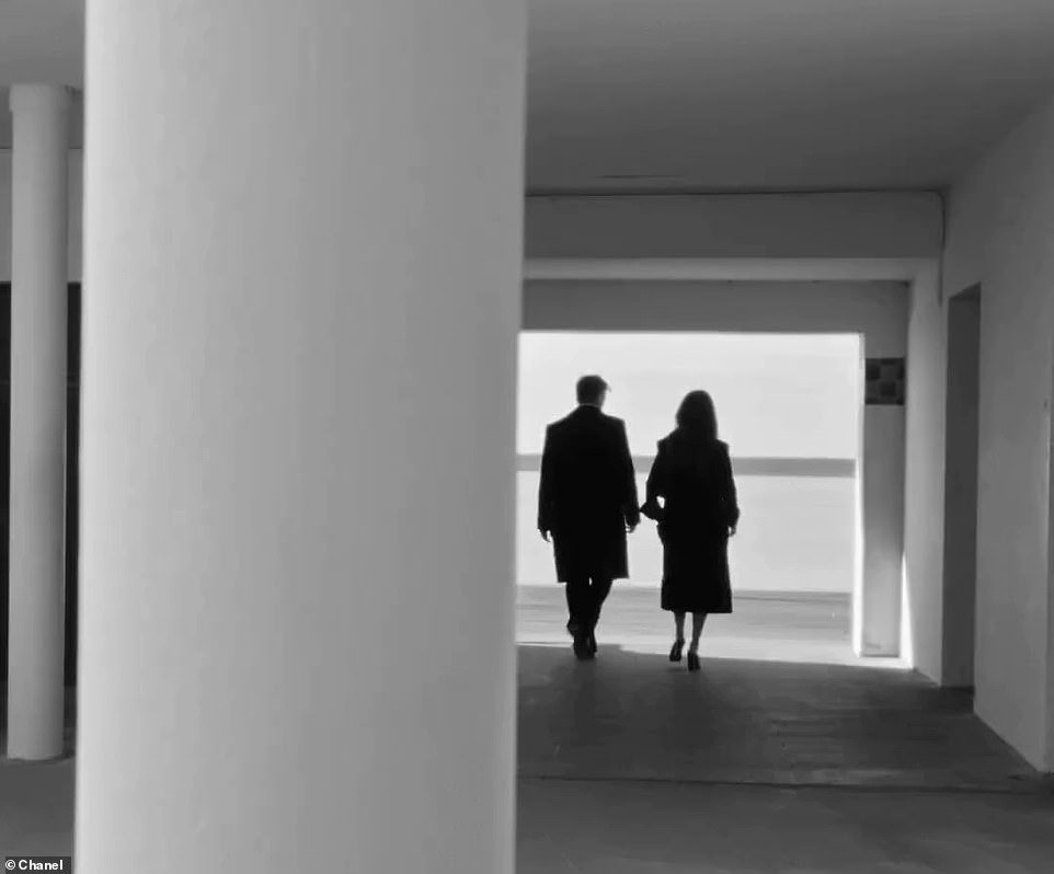 They walk together through a building that leads them to the sandy beach