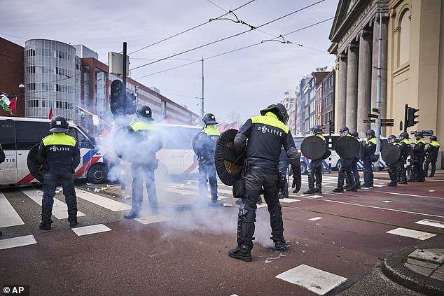 Protesters set off some fireworks as Dutch riot police form a line during a protest against the presence of Israeli President Isaac Herzog