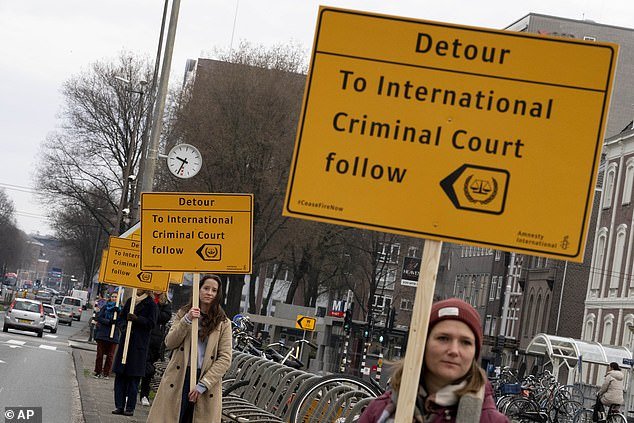 Protesters were seen walking along the route holding signs reading: 'Detour to the International Criminal Court'.