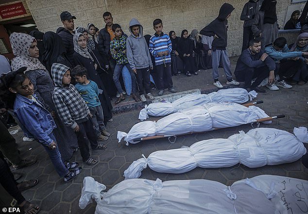 Relatives of the Al Atrash family mourn their covered bodies at Al Aqsa Hospital, following an Israeli airstrike in Deir Al Balah