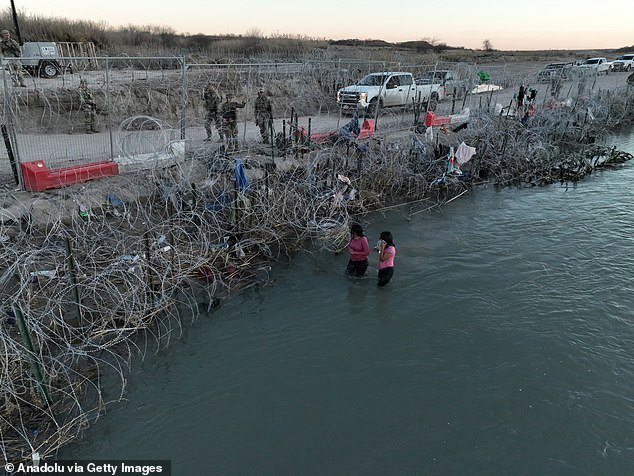 Two migrants struggle to cross the Rio Grande River at the Mexico-US border as the Texas National Guard takes security measures in Eagle Pass, Texas