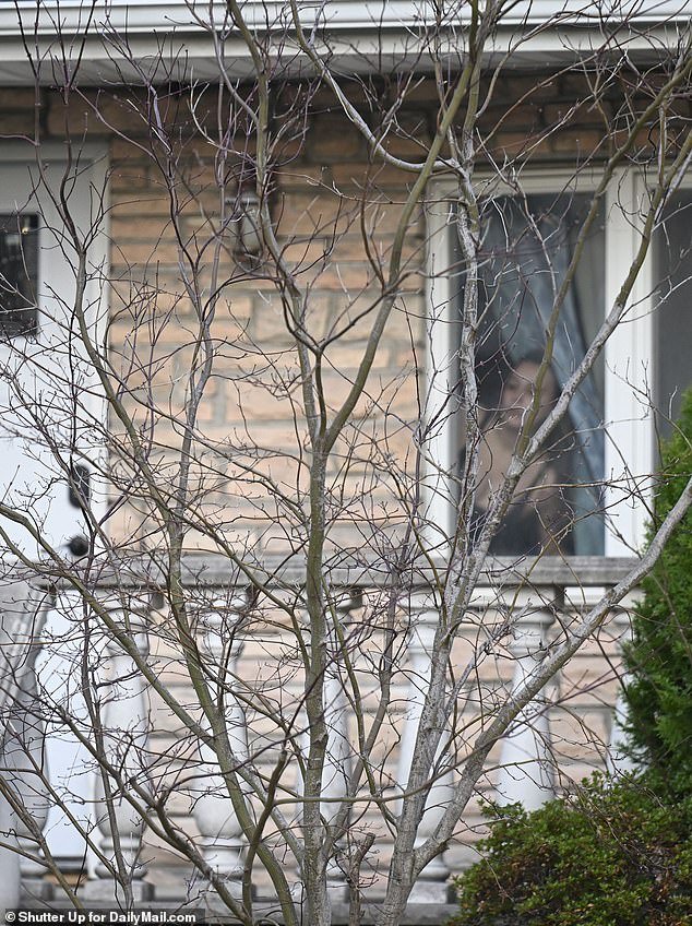 A woman crouched inside peers through the window and watches a confrontation Tuesday