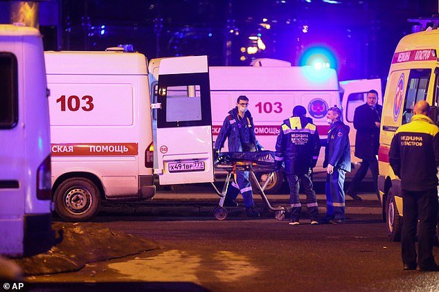 Medics transport the body of a victim in a waiting ambulance near the burning Crocus City Hall building on the western outskirts of Moscow