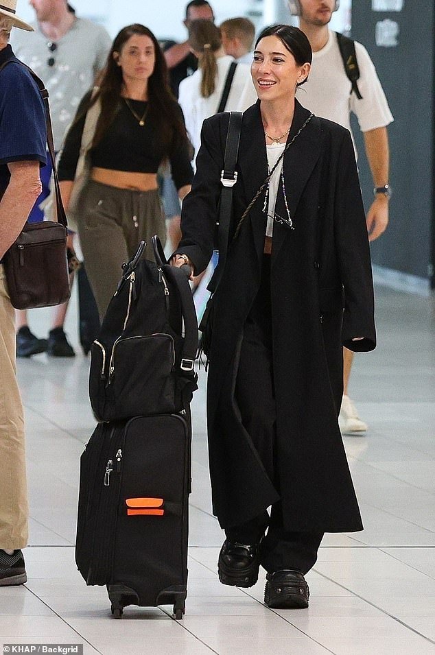 The pop singer carried a guitar as she left the airport, as well as a designer crossbody bag