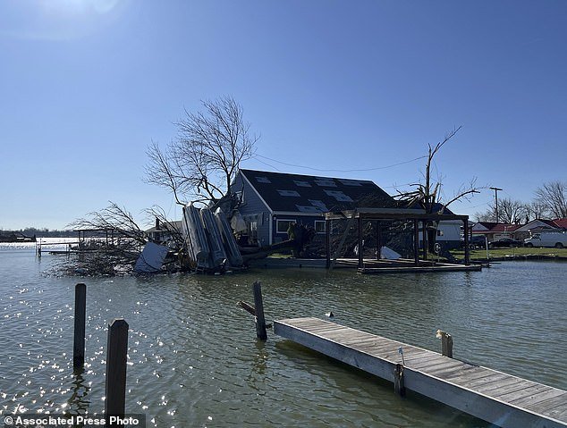A boat lies upside down in a tree on Orchard Island in Russells Point, Ohio, on Saturday, March 16, 2024