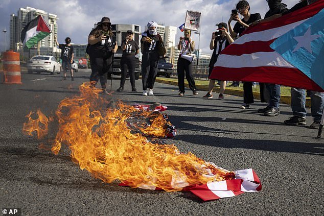 Protesters burn an American flag in the street during Harris' trip to Puerto Rico