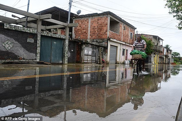 A man cycles through a flooded street on Sunday after a rainstorm hit Duque de Caxias, a town on the outskirts of Rio de Janeiro