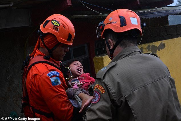 A Civil Defense member holds Ayla da Silva after the 4-year-old girl was rescued on Saturday morning