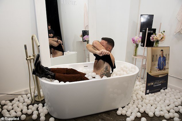 The interior designer then took off his vest as he went shirtless while sitting in a tub filled like a ball pit and posed for playful photos to celebrate his new venture.
