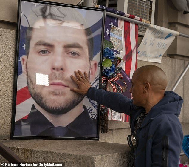 A 101 officer closes his eyes and touches the photo of slain NYPD officer Jonathan Diller.