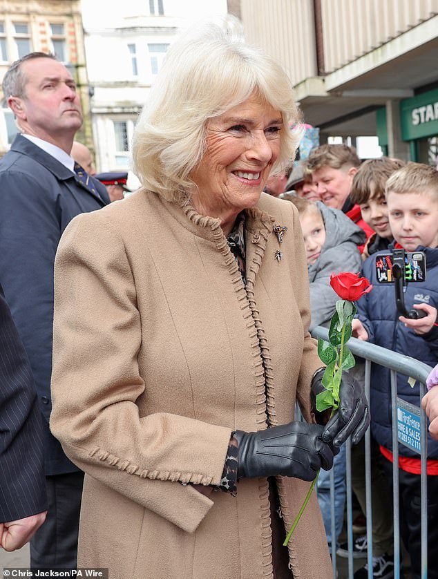 Queen Camilla smiles after receiving a red rose from Abi Crighton in Shrewsbury