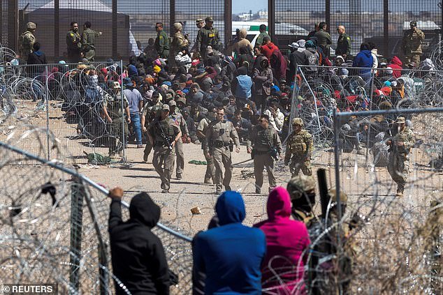 Illegal migrants break through barbed wire as they forcibly enter the United States through the southern border on March 21, 2024