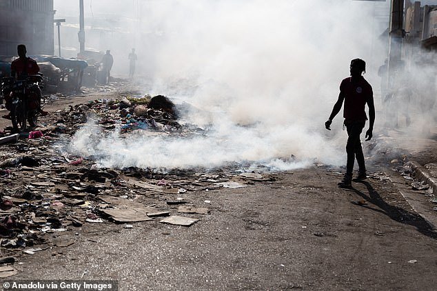 People burn garbage close to the bodies of the dead, while at least ten bodies of gang members lie in the streets after the gunfire between armed gangs in Petion-Ville